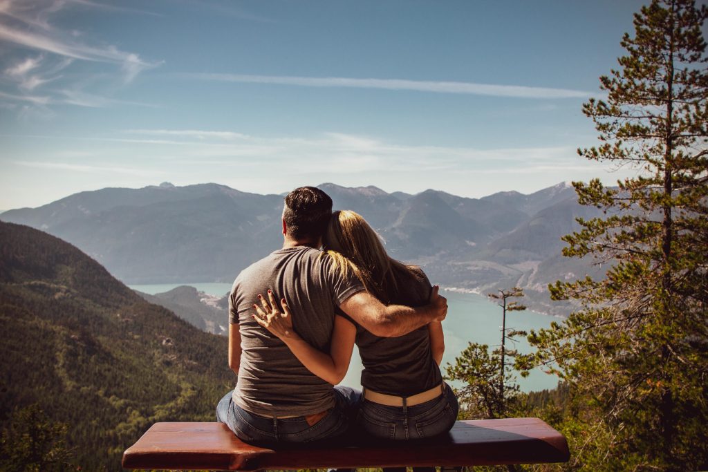 pexels-photo-1417255-1417255 Couple sitting on bench embracing scenic mountain view, embodying romantic nature escape.
